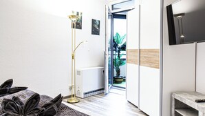 Ein modernes Schlafzimmer mit einem großen Bett, einer Stehlampe, einem Fernseher und Blick ins Freie.