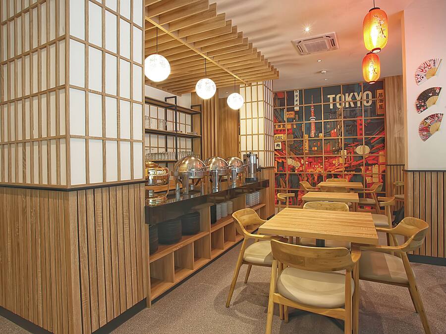 Interior de restaurante con paneles de madera, una barra con equipo de servicio de alimentos y mesas con sillas.