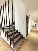 A modern interior with a staircase, wooden flooring, and white walls.