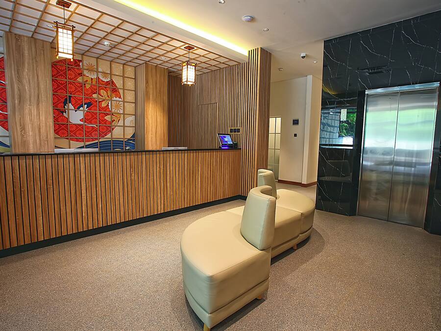 Eine moderne Lobby mit Holztresen, einer Sitzecke und einem Aufzug.