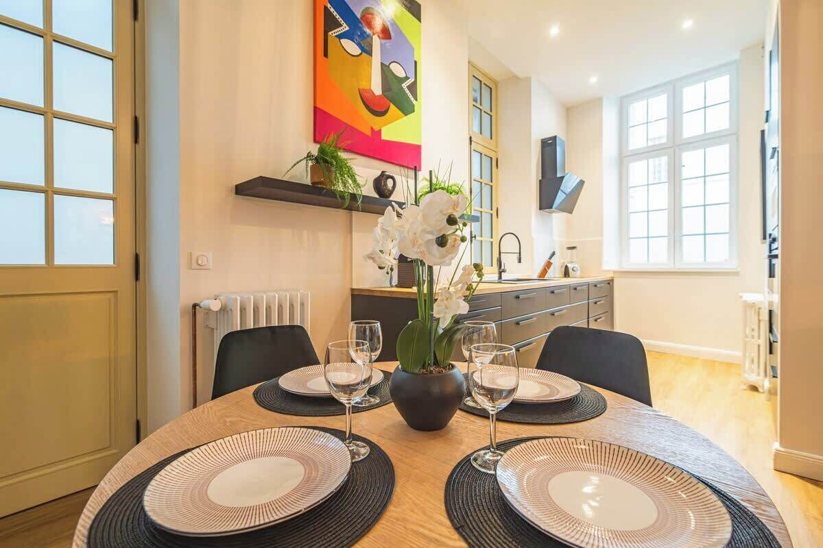 A dining table set with plates, glasses, and a vase of flowers.
