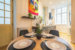 A dining table set with plates, glasses, and a vase of flowers. - MM Suites Loft Cathédrale (Reims)