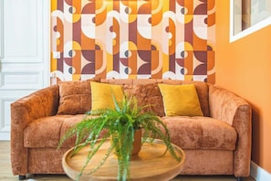 A room with a sofa, two yellow cushions, and a green plant on a wooden table.