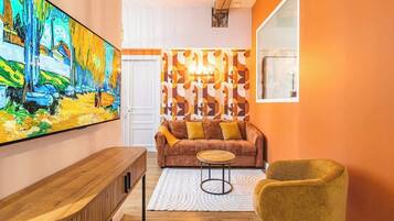 A living room with a large painting, a sofa with cushions, a coffee table, and a chair.