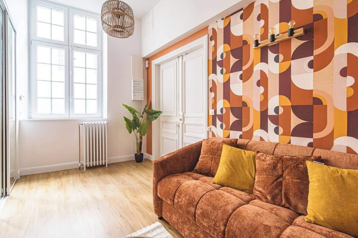 A room with a sofa, a radiator, a potted plant, and a patterned wall.