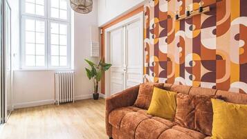 A room with a sofa, a radiator, a potted plant, and a patterned wall.