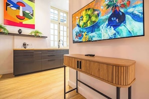 A modern kitchen with a wooden console table, a black cabinet, and a colorful abstract painting above the sink.