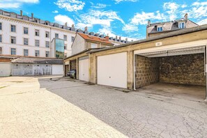 A building with a garage, a paved courtyard, and a brick wall.