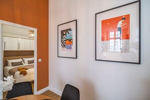 A modern room with a bed, a dining table, and two framed artworks on the wall.