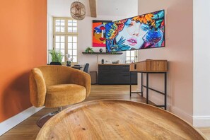 A modern living room with a sofa, a wooden coffee table, and a large painting on the wall. - MM Suites Loft Cathédrale (Reims)