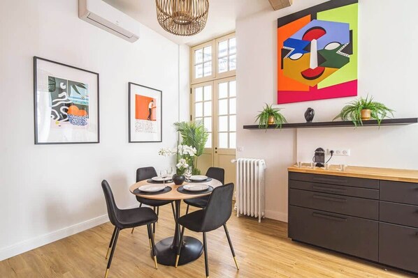 A modern kitchen with a dining table, chairs, and artwork on the walls.