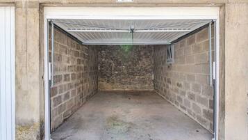 A garage with a metal roof, brick walls, and a concrete floor.