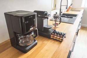 A kitchen with a coffee maker, a coffee grinder, and a coffee bean container. - MM Suites Loft Cathédrale (Reims)