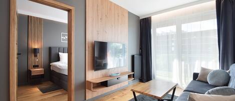 A modern living room with a flat-screen TV, wooden shelving, a sofa, and a dining table.