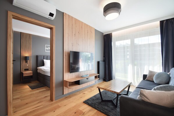 Una sala de estar moderna con televisor de pantalla plana, estanterías de madera, un sofá y una mesa de comedor.