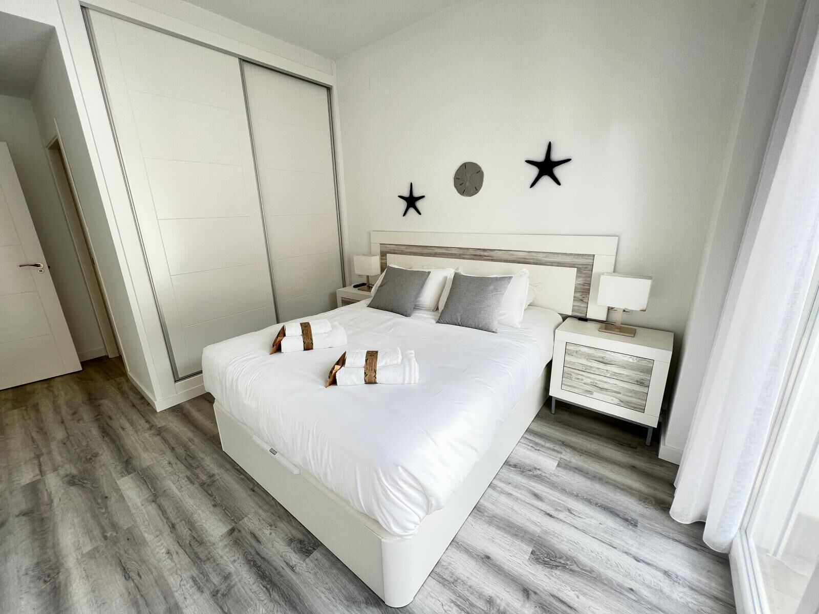 Et moderne hotelværelse med en stor seng, et natbord, et vægur og stjernepynt.