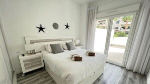 A modern bedroom with a large bed, a nightstand, a lamp, and a view of the outside. - PUSHE Playa Granada Beach & Golf 12 (Motril)