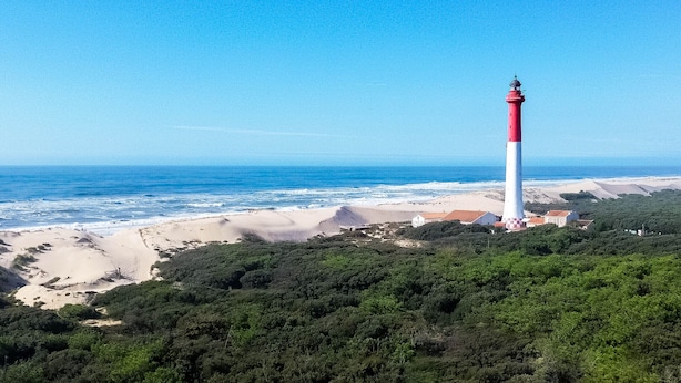 A coastal landscape with a lighthouse, beach, and dense greenery. - Single-story house 4 rooms near sea, 6 people, patio (La Palmyre)