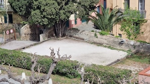 Un patio con un árbol, un muro de piedra y un edificio con balcones.