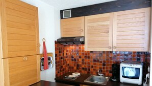 Eine Küche mit Holzausstattung, einer gefliesten Spritzschutzwand, einer Mikrowelle und einem Spülbecken.