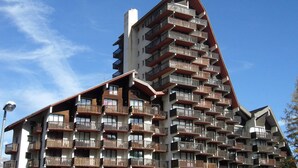 Ein mehrstöckiges Hotel mit Balkonen, einem geneigten Dach und blauem Himmel im Hintergrund.