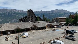 Un chalet de montagne doté d’un parking, de bâtiments en bois et offrant une vue sur des montagnes enneigées.