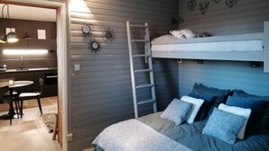 Une chambre compacte comprenant un lit superposé, un petit bureau et un coin cuisine.