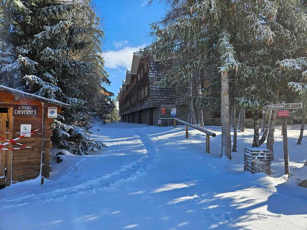 A snow-covered street with a wooden building labeled "Local Cheverny 1" and a sign pointing towards "Cheverny I".