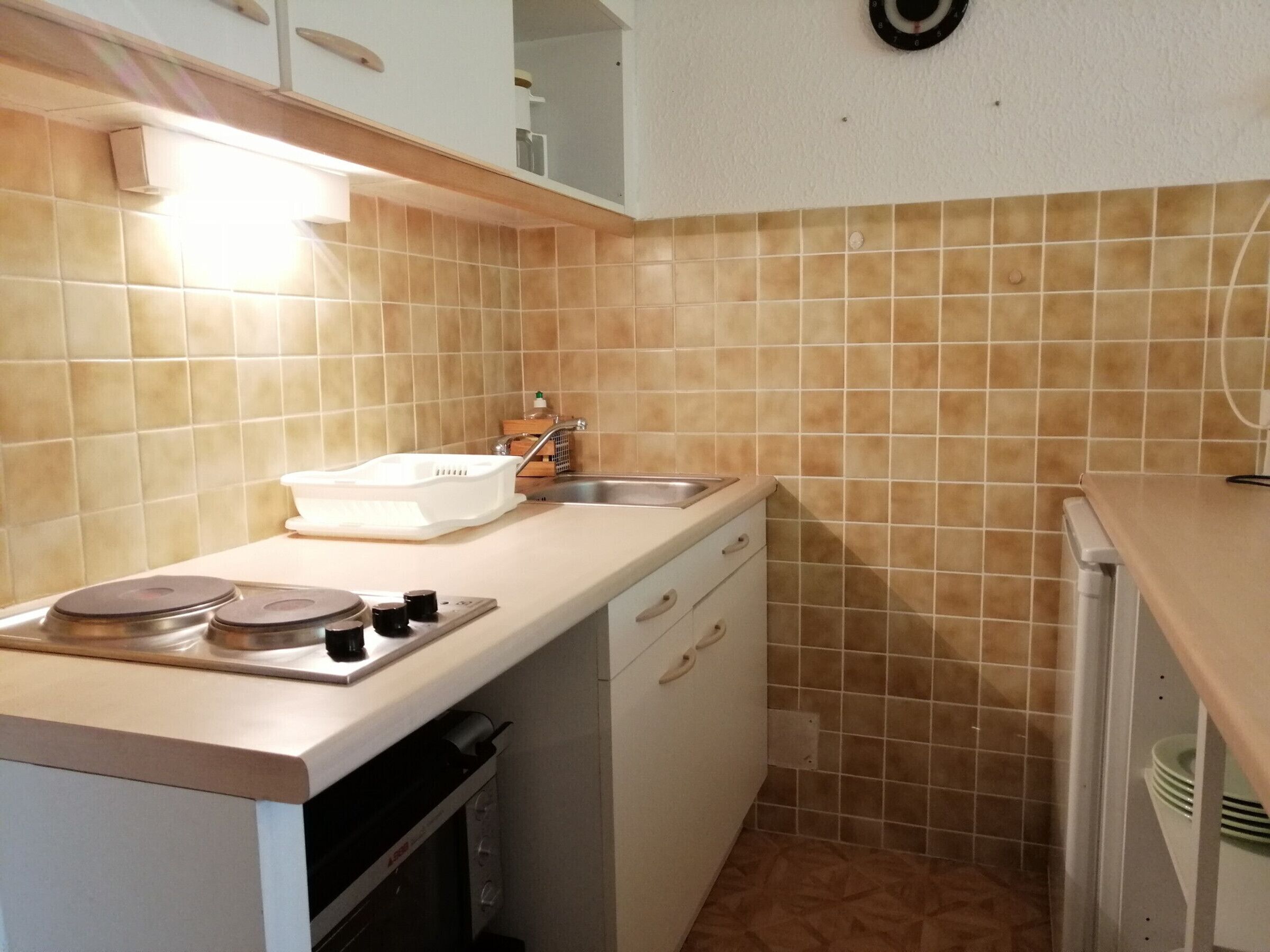 Una cocina compacta con estufa, fregadero y lavavajillas.