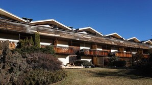 A multi-story hotel with a wooden facade, balconies, and a grassy courtyard. - Cozy studio for 2 near slopes in Pra-Loup (Pra-Loup)