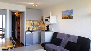 Un espacio habitable compacto con kitchenette, comedor y sofá.