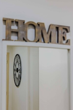 Una puerta blanca con un detalle decorativo de metal negro y la palabra 'HOME' en letras grandes en la parte superior.