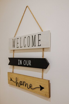 A wooden sign with the words "WELCOME IN OUR home" hanging on a wall. - Marina Rey – 400m from beach, Côte d’Azur vibe (Villeneuve-Loubet)