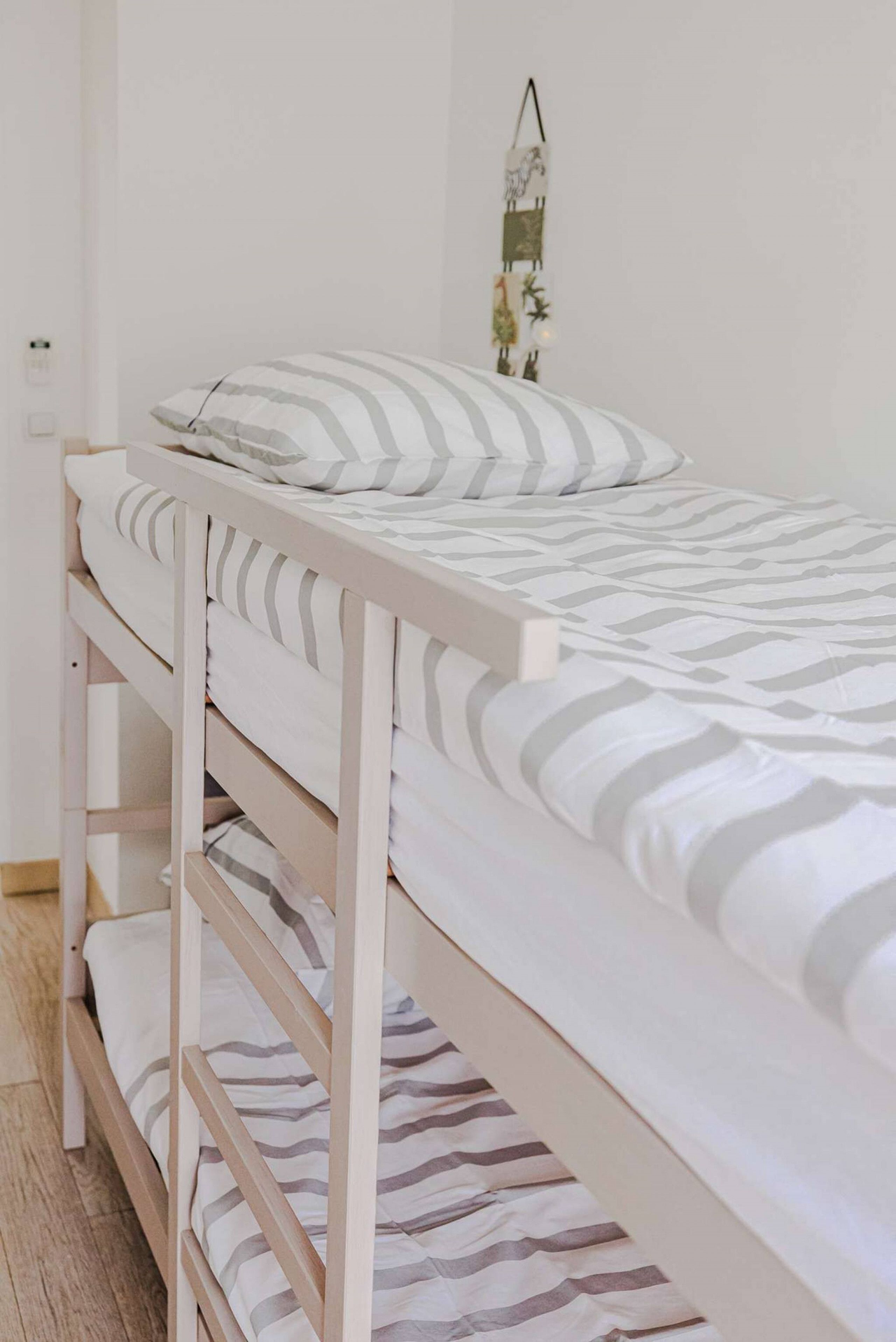 A bunk bed with white bedding and striped pillows.