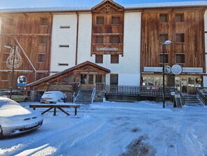 A building with a wooden facade, a sign for 'Le Chamois', and a 'SNACK BAR' sign. - Studio for 4, slopeside with south-facing balcony (Pra-Loup)