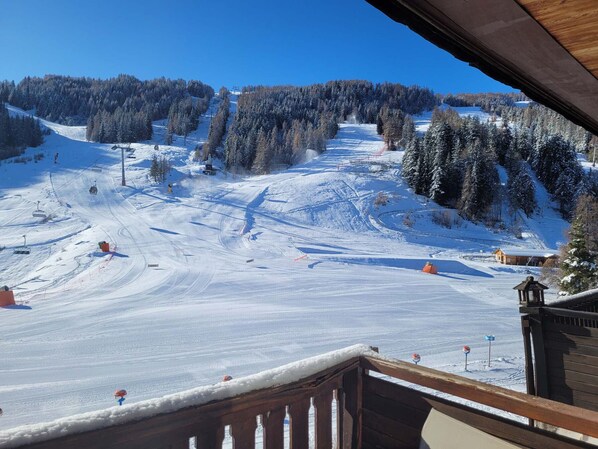 A snowy ski slope with a wooden cabin and a ski lift in the background.
