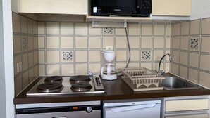 Et køkken med mikrobølgeovn, komfur, kaffemaskine og vask.