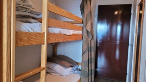 A bunk bed room with a wooden headboard, a door, and a curtain.