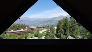 A view through a triangular window of a mountainous landscape with buildings and trees. - 2-room apartment for 4, balconies, mountain view, parking (Pra-Loup)