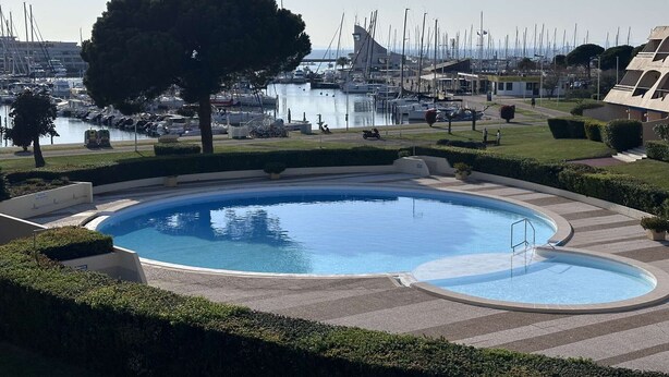 A swimming pool with a view of a marina and boats. - Charming Studio for 4 with Sea View, Pool, and Parking Near the Beach (Le Grau-du-Roi)