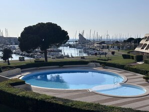 A swimming pool with a view of a marina and boats. - Charming Studio for 4 with Sea View, Pool, and Parking Near the Beach (Le Grau-du-Roi)
