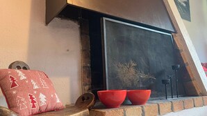 A fireplace with a screen, two red bowls, and a wooden chair with a red cushion.