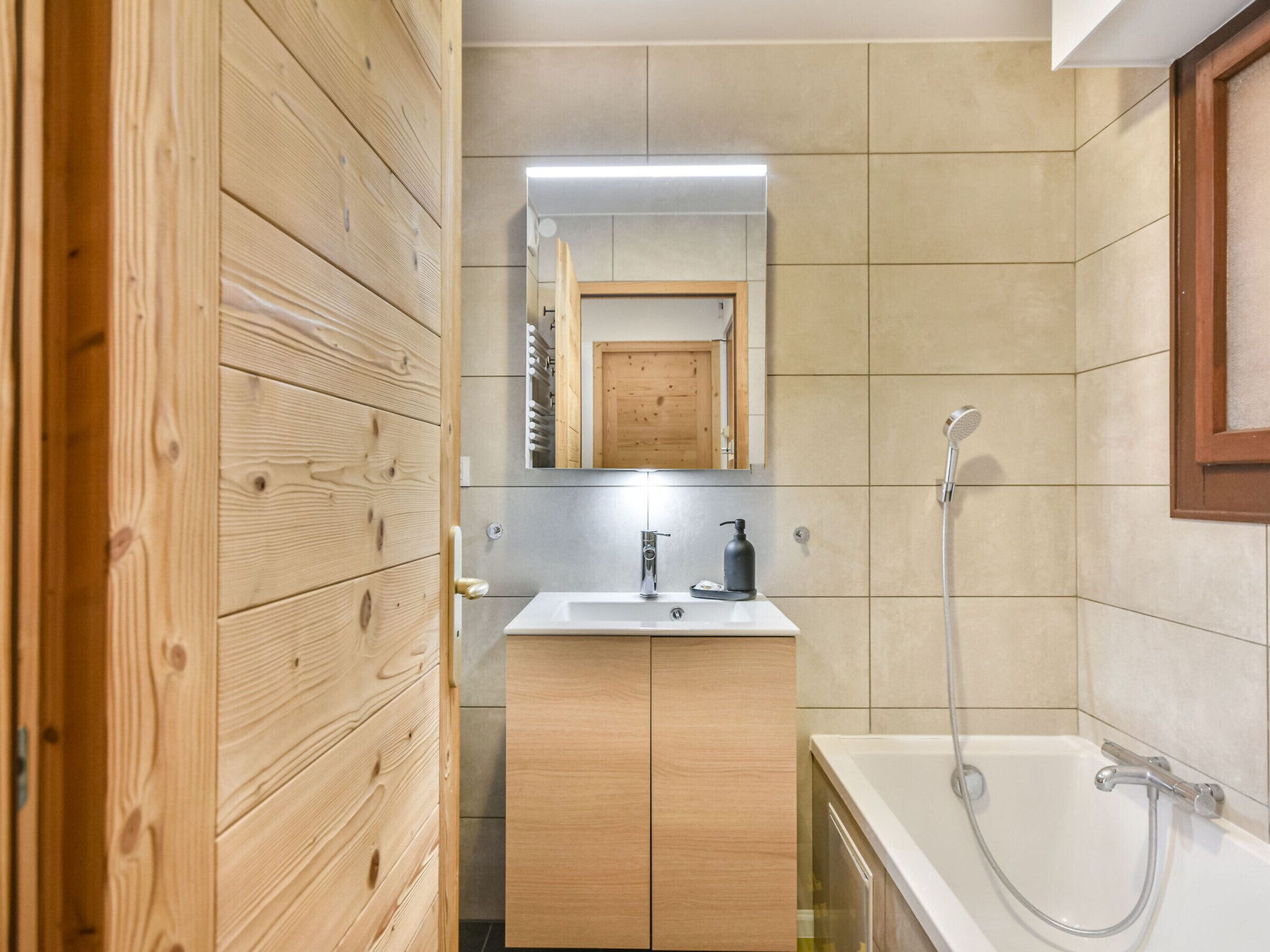 A modern bathroom with wooden cabinetry, a white sink, a mirror, and a shower.