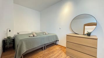 Ein Schlafzimmer mit Bett, Kommode, Spiegel und Nachttisch mit Lampe.