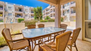 Un balcone con un tavolo in vetro e sedie in vimini, affacciato su una zona residenziale con diversi condomini.