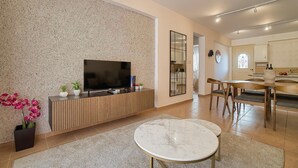 Un soggiorno moderno con una TV a schermo piatto su un mobile in legno, un tavolino rotondo in marmo e una parete strutturata.