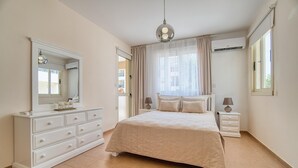 Una camera da letto con un letto, una cassettiera, uno specchio, una lampada e un condizionatore d'aria.