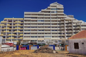 Un hotel a più piani con balconi, un tetto piano e un cielo azzurro intenso.