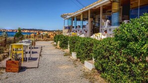 A coastal property with a covered outdoor seating area, a gravel path, and a view of the sea. - Vacation Apartment In Portimao (Portimão)