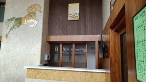 A hotel reception desk with a wooden counter, a reception area, and a wall-mounted sign. - Hotel Darwin City  (Port Blair)